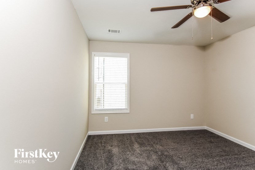 an empty room with a ceiling fan and a window