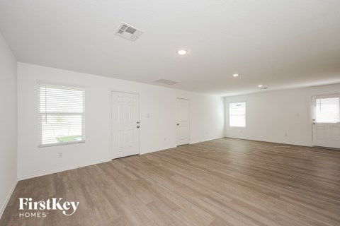 A spacious room with wooden flooring and white walls.