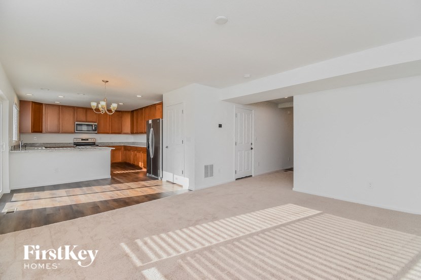 an empty living room and kitchen with white walls and wood cabinets