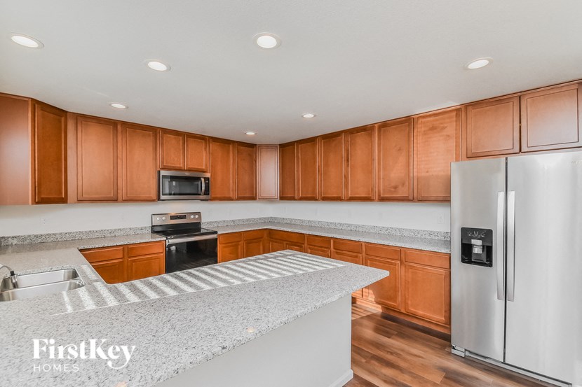 a kitchen with granite countertops and wooden cabinets and stainless steel appliances