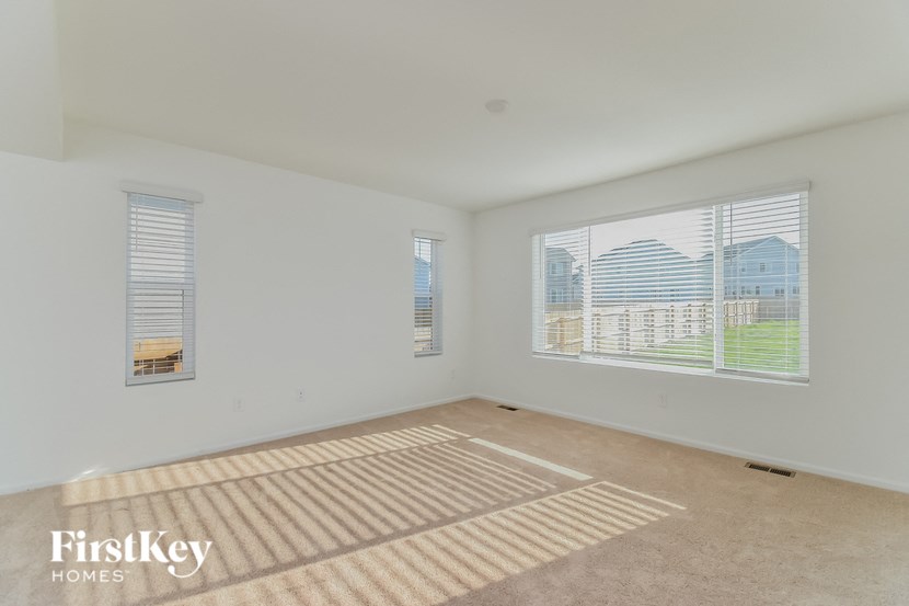 a spacious living room with two large windows and a rug on the floor