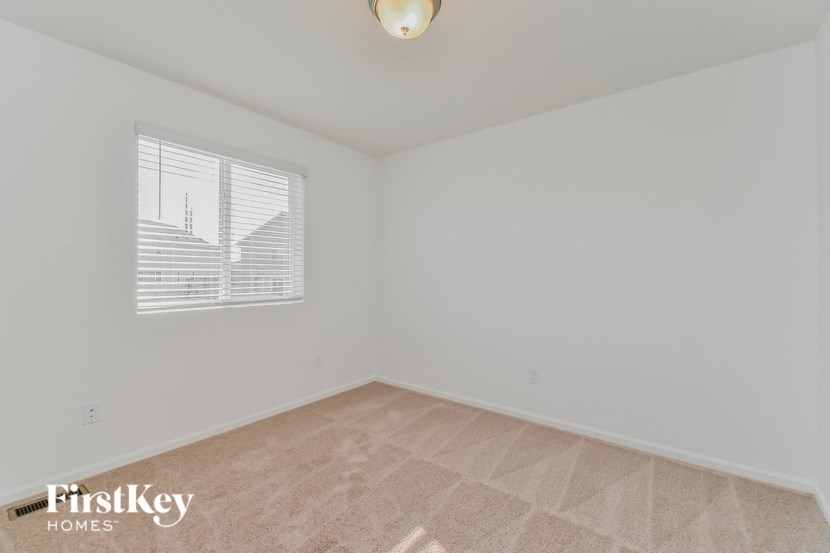 the living room of an empty home with white walls and a window