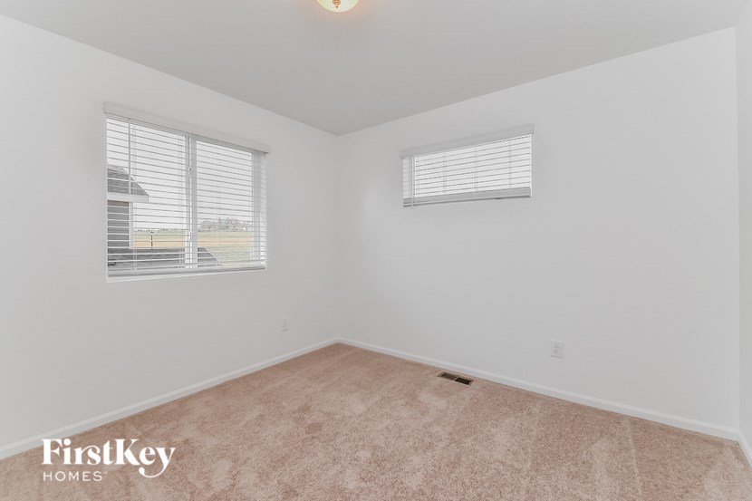 the living room of a home with two windows and beige carpeting