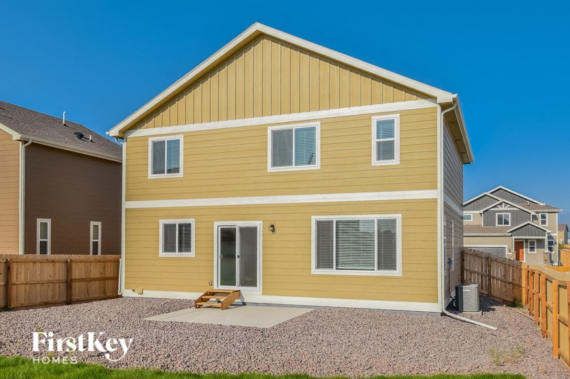 the backyard of a yellow house with a wooden fence