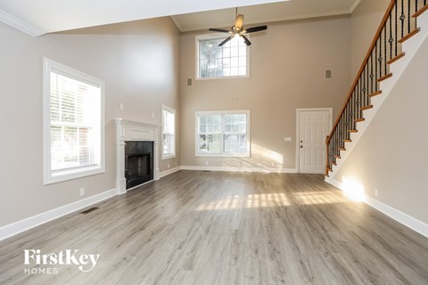 A spacious living room with a fireplace and a staircase.