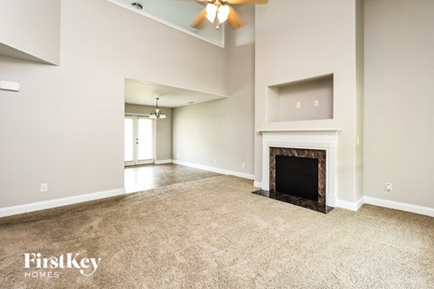 A spacious living room with a fireplace and a ceiling fan.