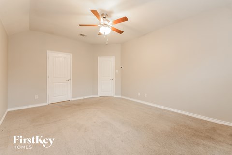 a spacious living room with carpet and a ceiling fan