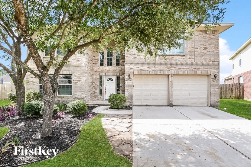 a white brick house with two garage doors and a sidewalk