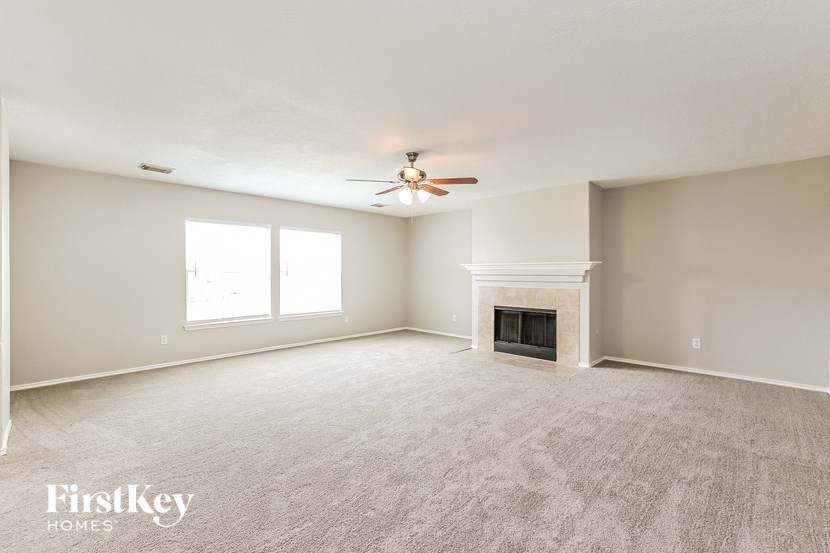 an empty living room with a ceiling fan and a fireplace