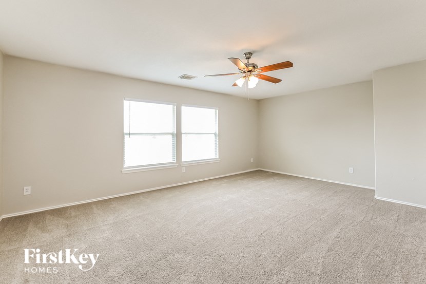an empty living room with a ceiling fan and a window
