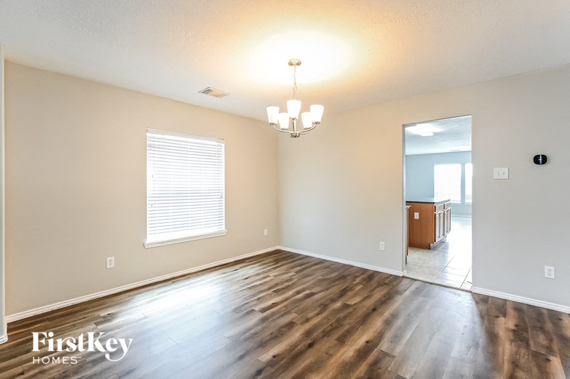 an empty living room with a hard wood floor and a chandelier