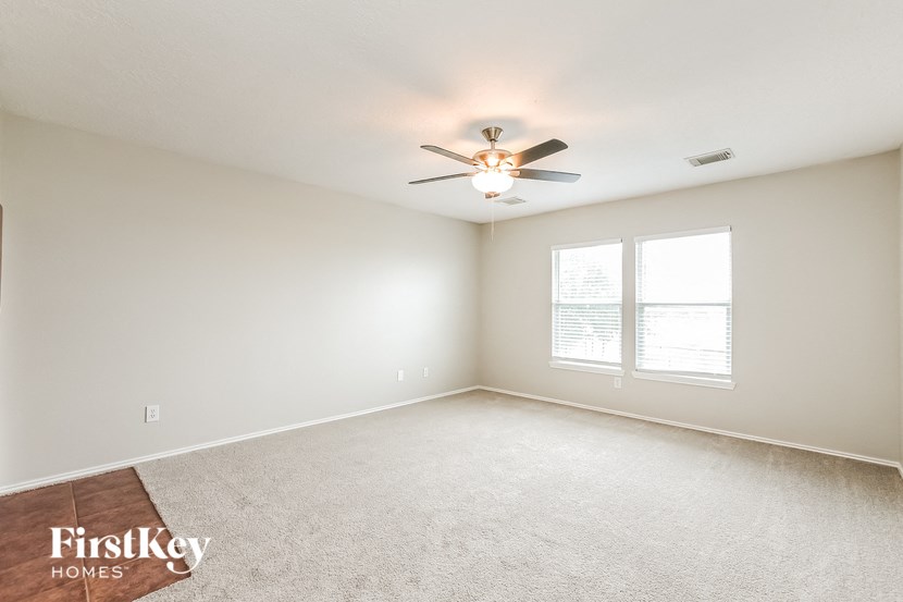 an empty living room with a ceiling fan and a window
