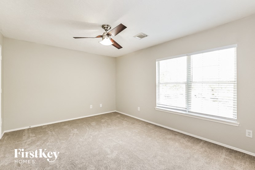 a bedroom with a ceiling fan and a large window