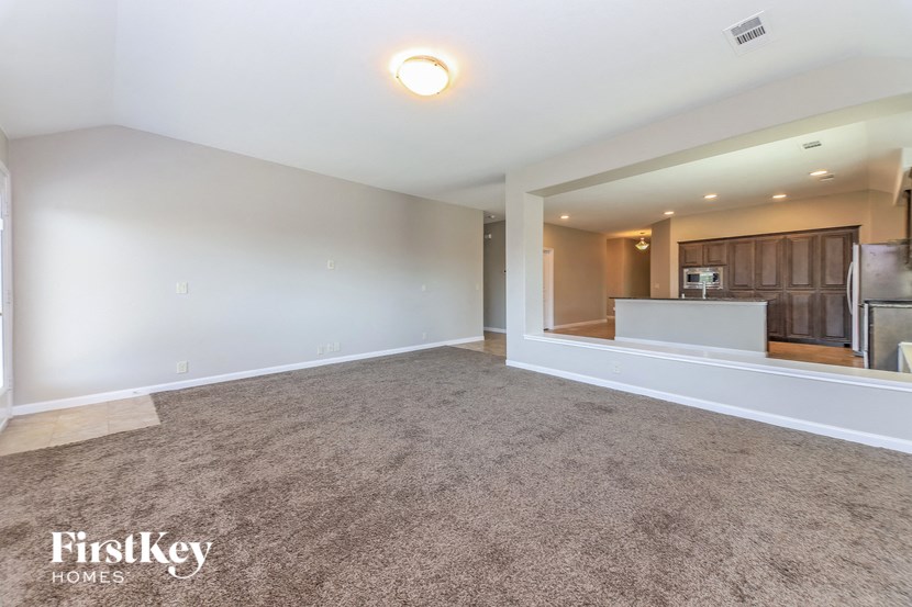 an empty living room and kitchen with white walls and carpet