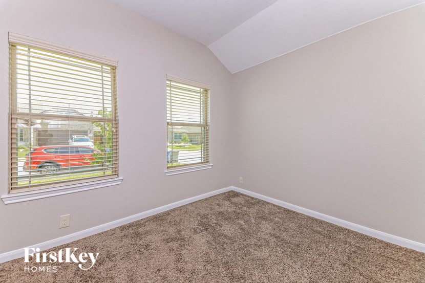 an empty bedroom with two windows and a carpet