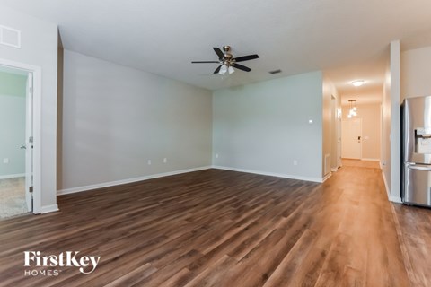 A spacious room with wooden floors and a ceiling fan.