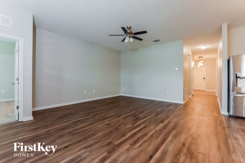 A spacious room with wooden floors and a ceiling fan.