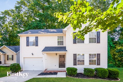 a white house with black shutters and a tree