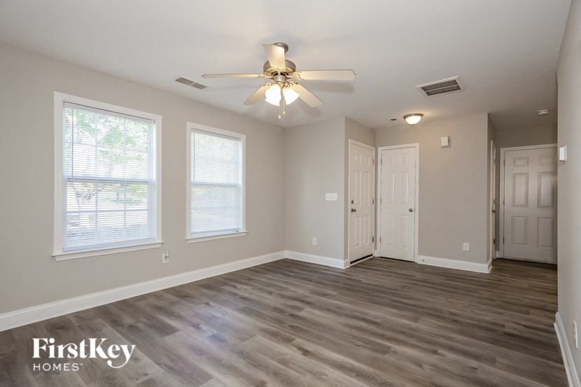 an empty living room with a ceiling fan and two windows