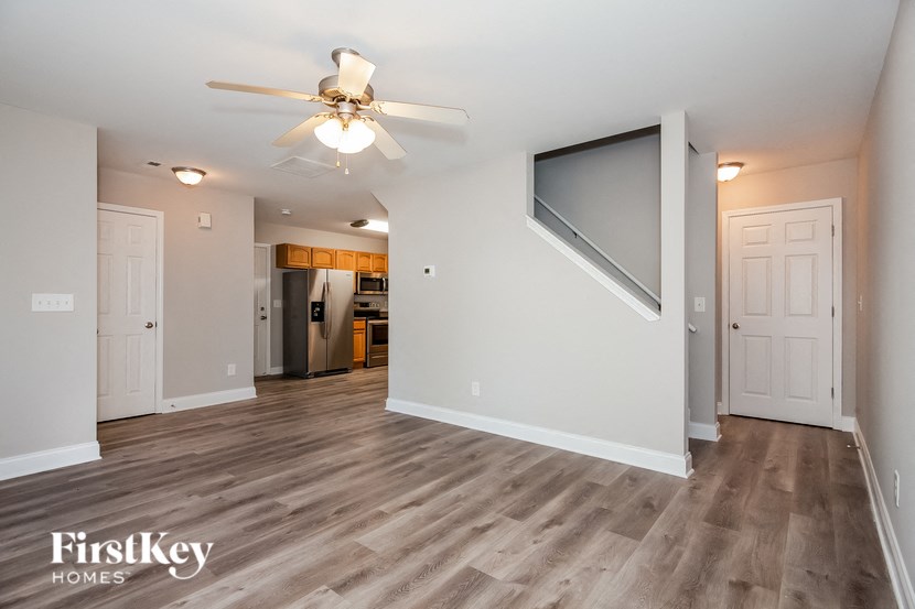 an empty living room with a ceiling fan and a tv
