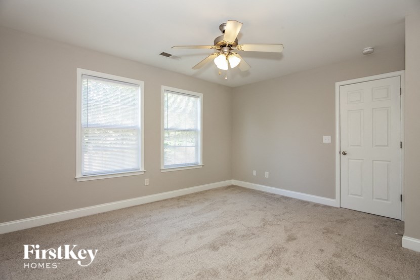 an empty bedroom with a ceiling fan and two windows