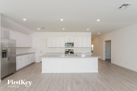 A modern kitchen with a stainless steel refrigerator and white cabinets.