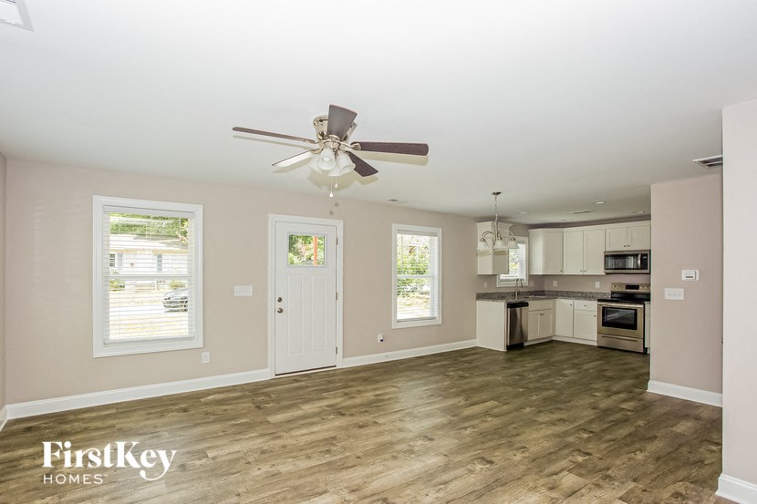 a living room with a ceiling fan and a kitchen