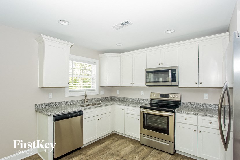 a kitchen with white cabinets and granite counter tops and stainless steel appliances