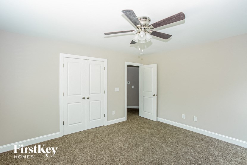 a bedroom with a ceiling fan and a door to a closet