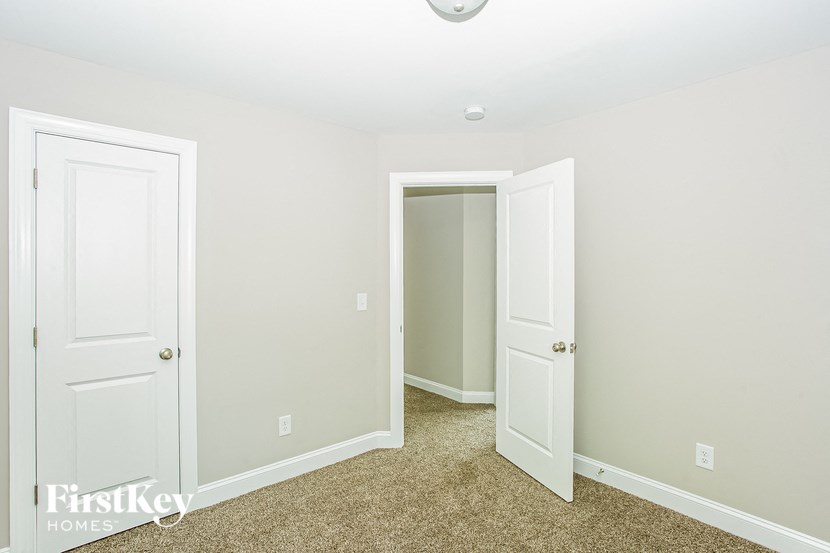 a bedroom with two doors and a closet and a carpeted floor