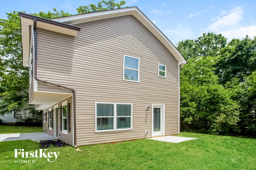a view of the back of a house with grass and trees