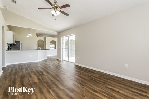 A spacious room with wooden floors and a ceiling fan.