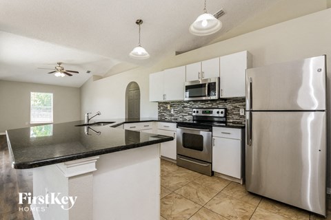 A kitchen with a stainless steel refrigerator and a black counter top.