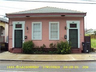 a pink house with three doors and a sidewalk