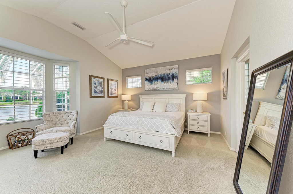 a bedroom with a white bed and a mirror