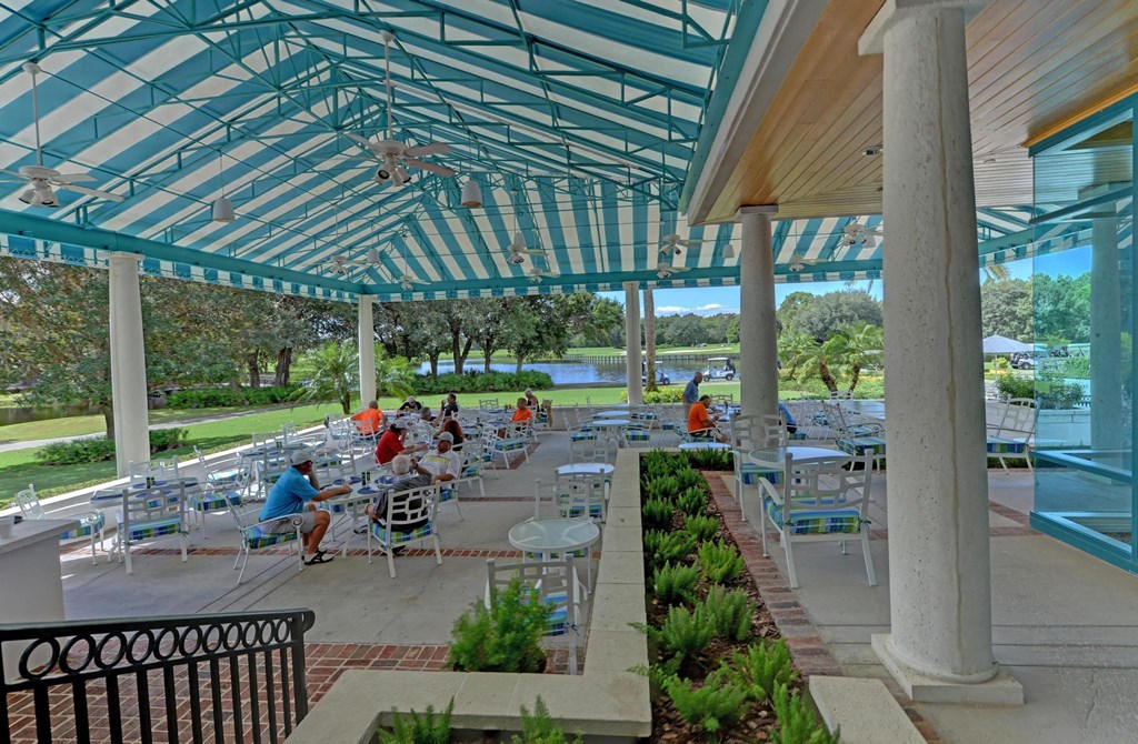 a covered patio with tables and chairs and a pool