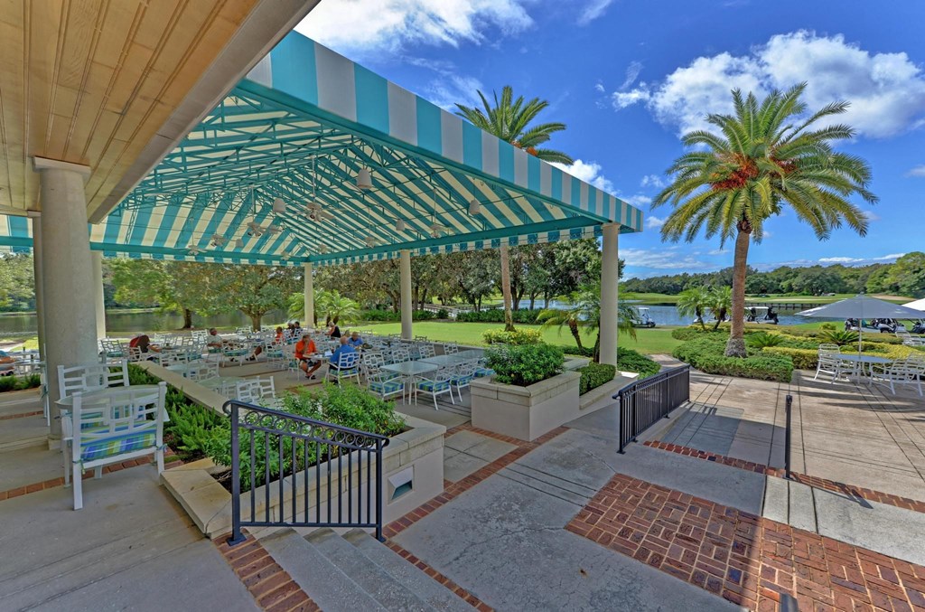 a covered patio with tables and chairs under awning