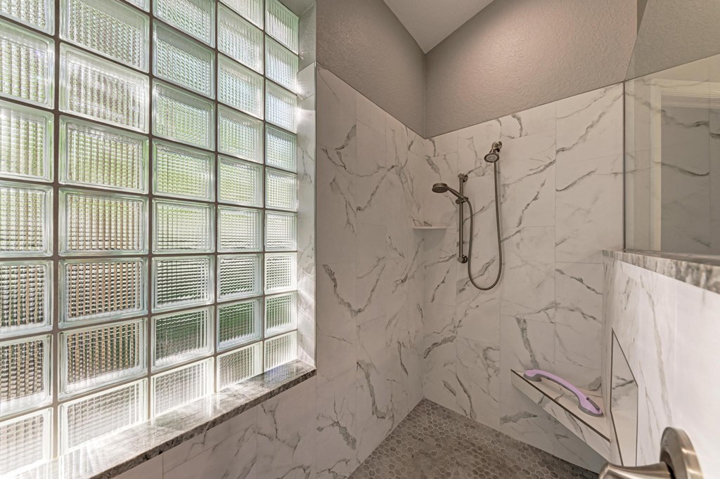 a marble bathroom with a shower and a glass block wall