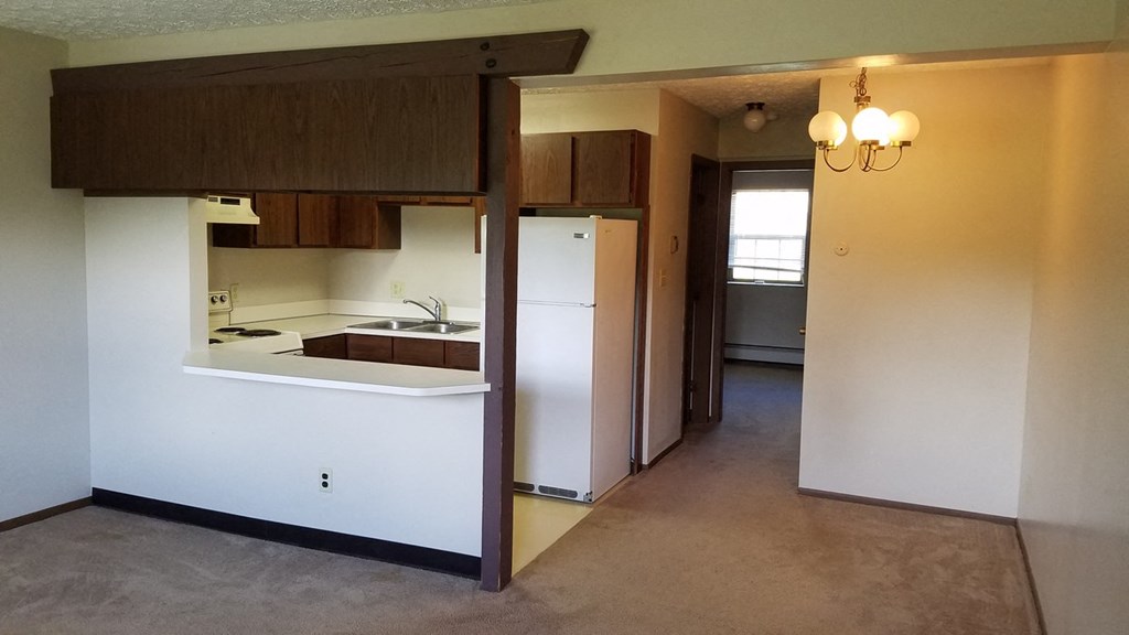 an empty kitchen and living room with a refrigerator and a sink
