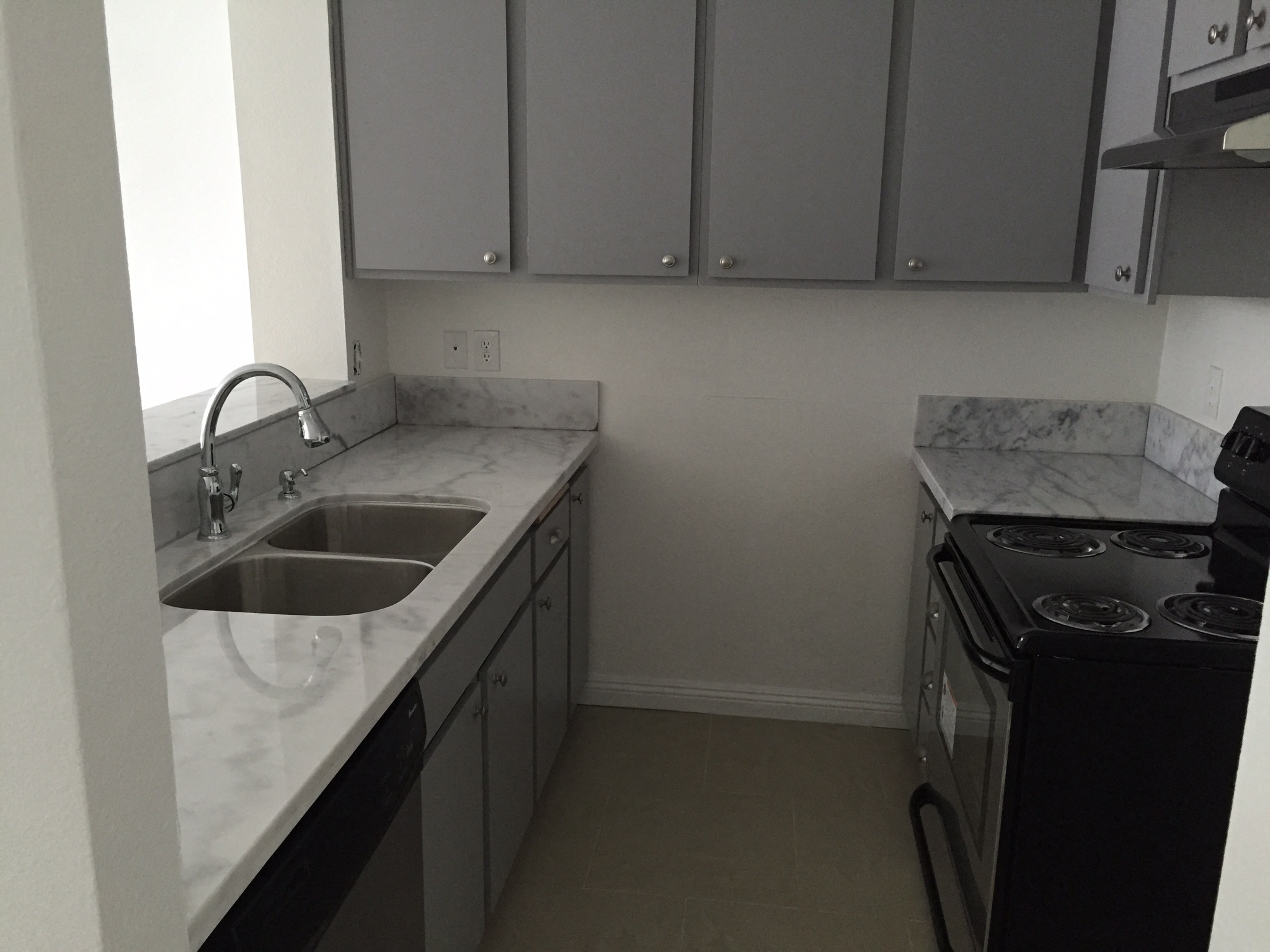 an empty kitchen with marble counter tops and a sink