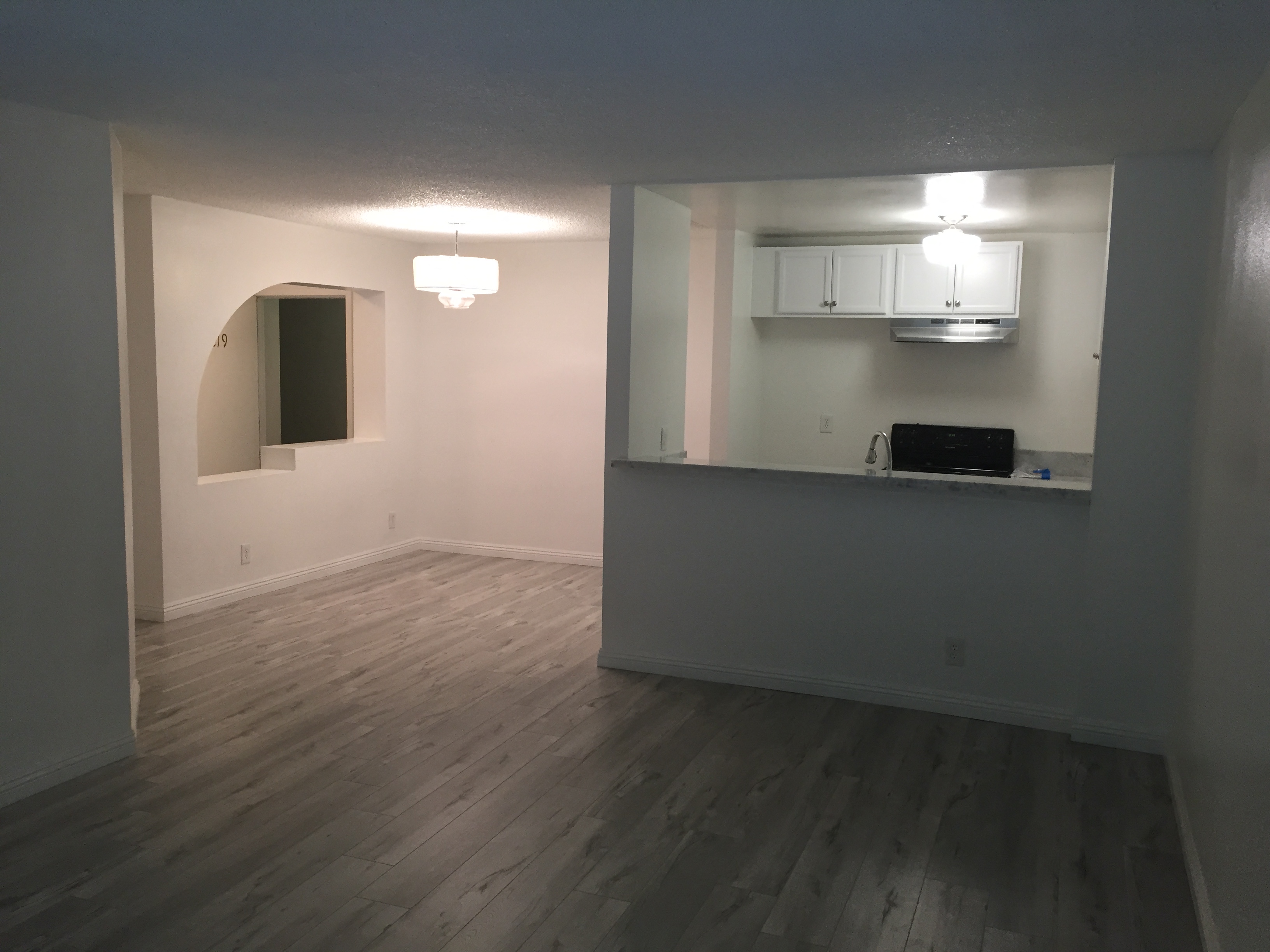 an empty living room with hard wood floors and a window
