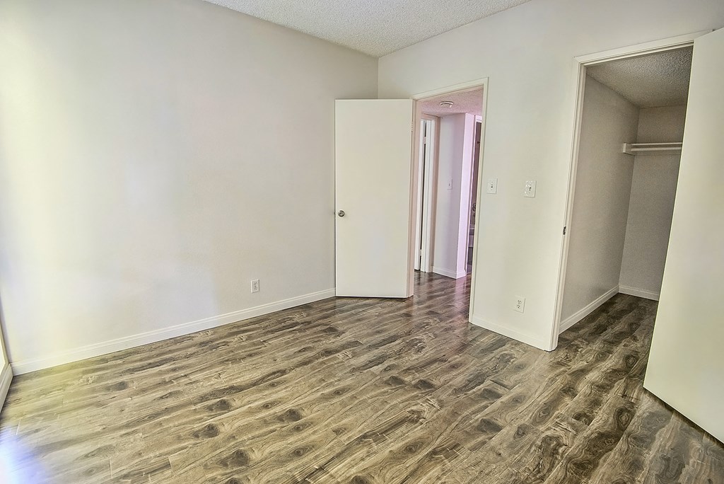 an empty living room with wood flooring and white walls