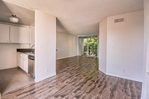an empty kitchen and living room with a wood floor