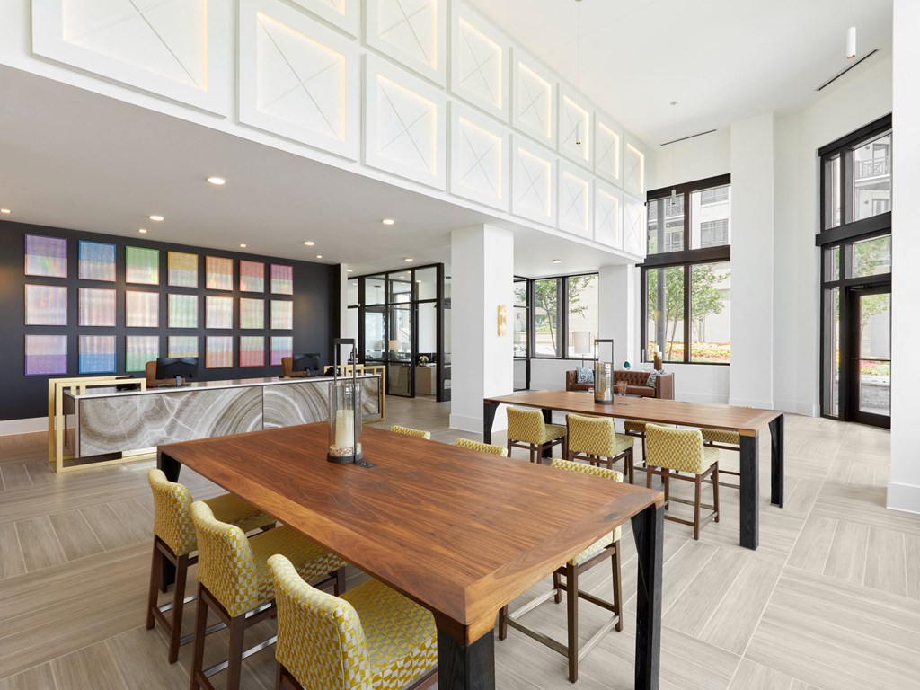a communal area with tables and chairs and a kitchen in the background