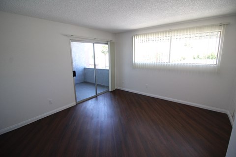 an empty living room with wood floors and a window
