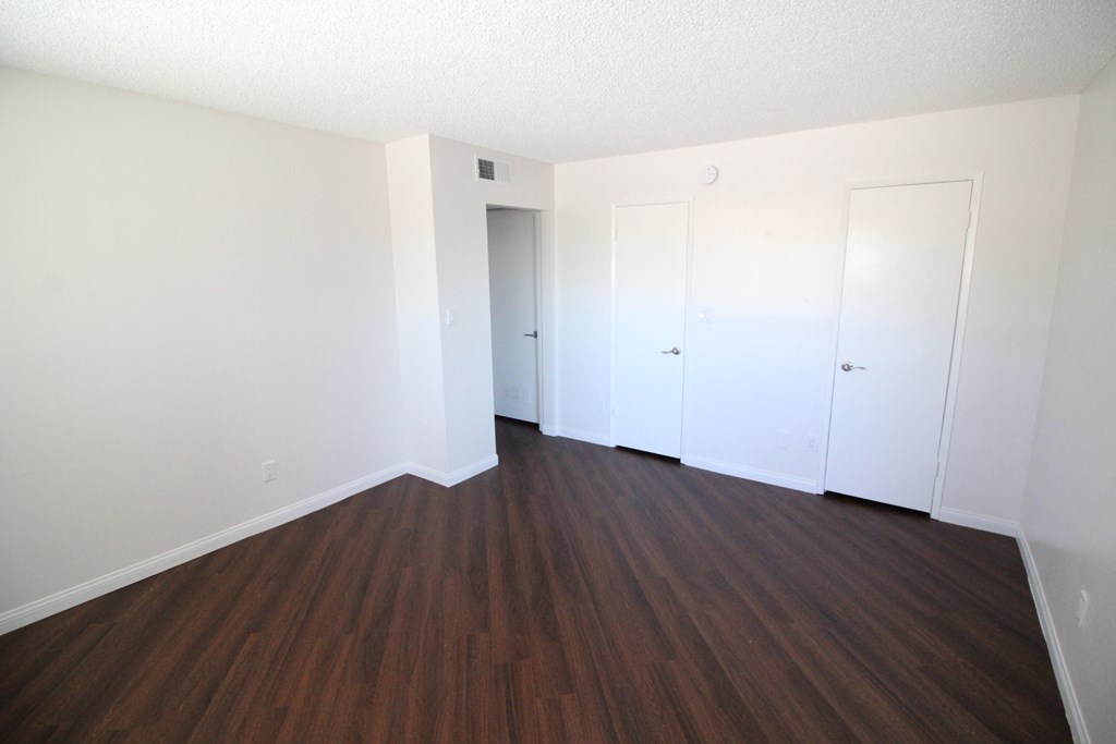 an empty living room with wood floors and white walls