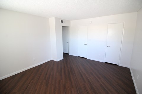 an empty living room with wood floors and white walls