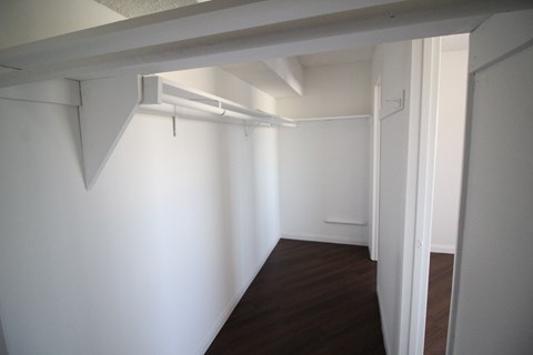 an empty room with white walls and a wooden floor and a white closet