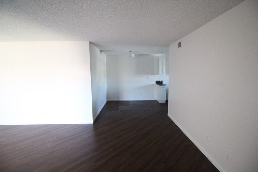 an empty living room with wood floors and white walls