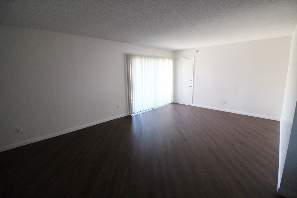 an empty living room with wood floors and white walls
